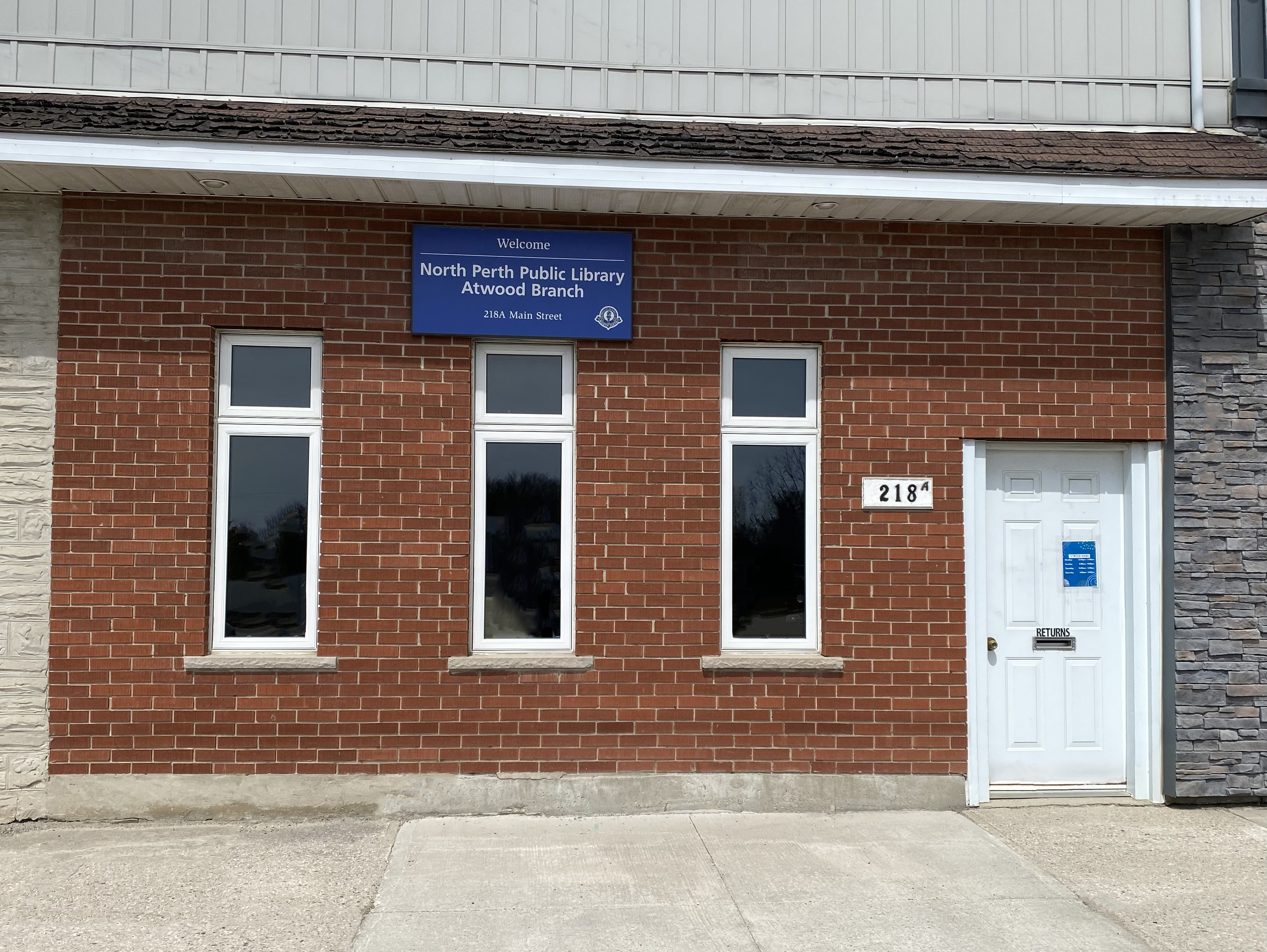 red brick storefront with blue sign above three windows